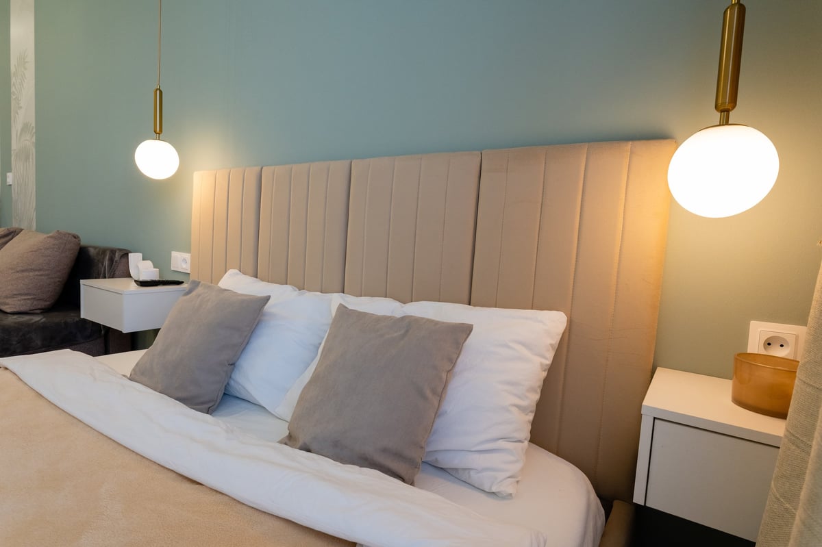 A cozy bedroom with comfy bed, stylish nightstand, and warm lamp