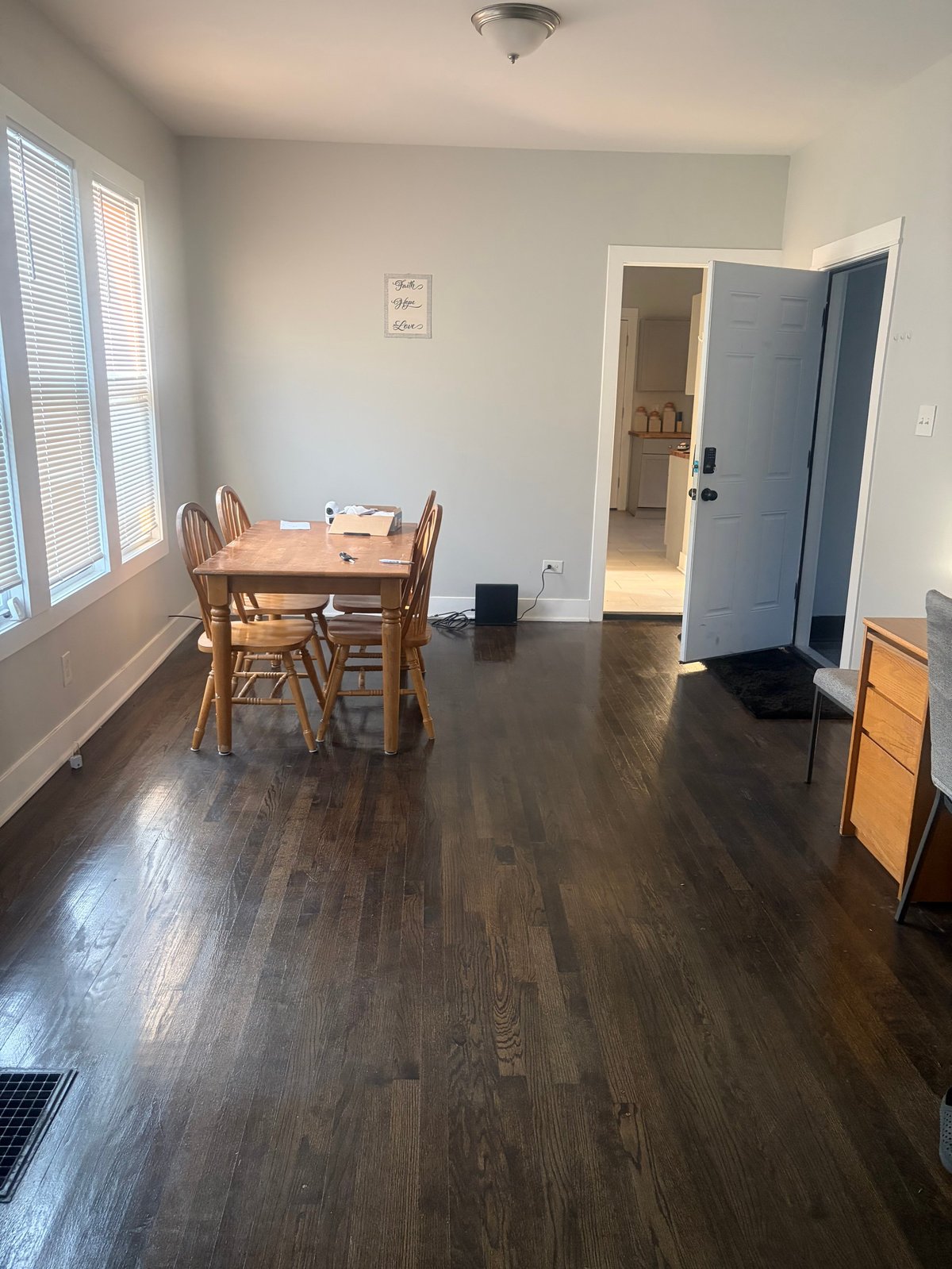 Spacious apartment living room with hardwood floors, wooden dining table with chairs, and open doorways leading to other rooms