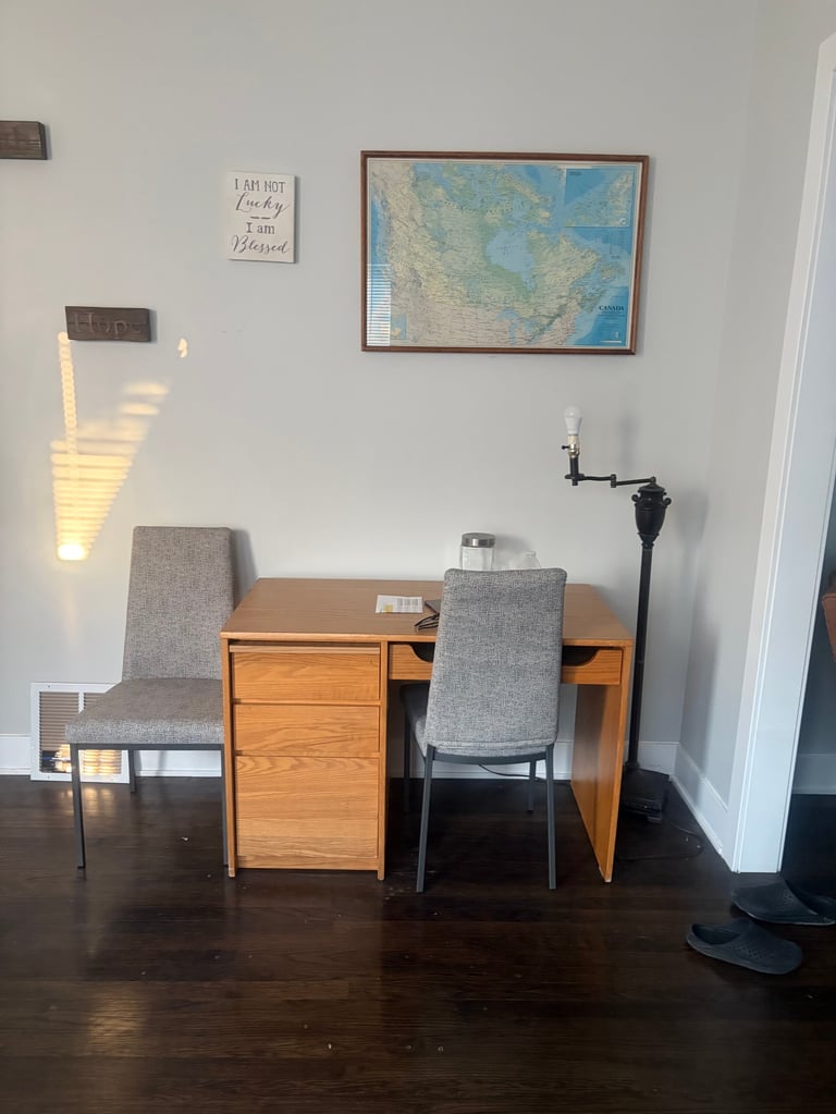 Minimalist office workspace with wooden desk, two gray chairs, wall-mounted map, and white walls in a modern interior